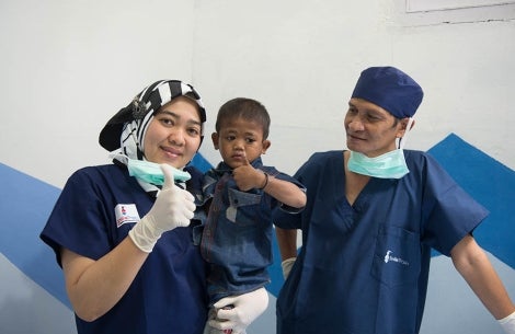 Dua rekan Smile Train tersenyum dan mengacungkan jempol kepada pasien penderita sumbing