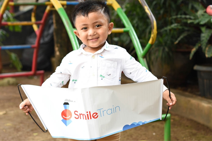 Cleft-affected patient smiling and holding a Smile Train banner